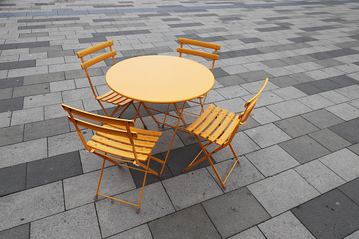 An unoccupied group with outdoor cafe furniture.