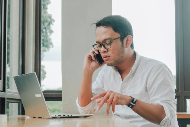 istock Young Asian businessman talking on a smartphone at a desk at caffe 1409906833