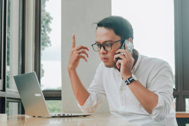 istock Young Asian businessman talking on a smartphone at a desk at caffe 1409907278