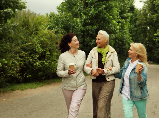 istock Three cheerful pensioners are walking in the park, having fun talking and drinking coffee. 1409907658