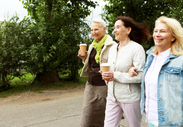 istock Three cheerful pensioners are walking in the park, having fun talking and drinking coffee. Friendship is priceless. 1409908207