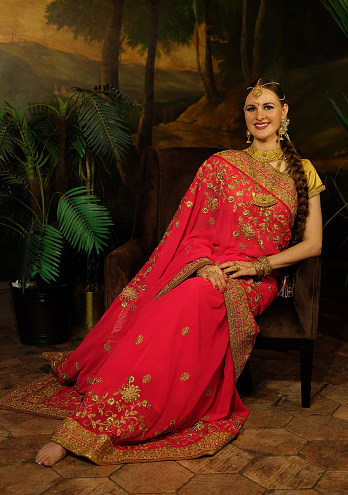 Portrait of beautiful indian female. Young hindu woman model kundan jewelry. Traditional Indian costume red saree.