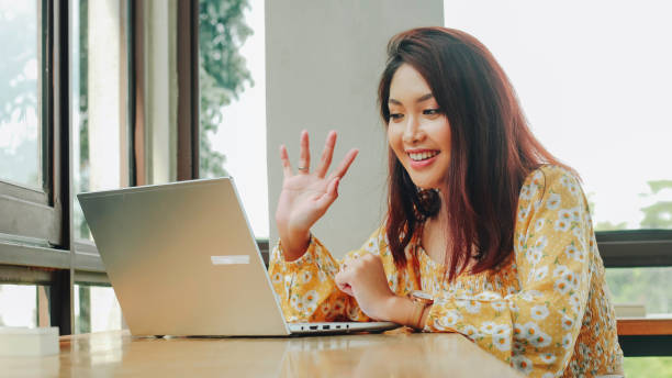 istock Young Asian woman doing video conference on laptop computer while sitting at the cafe, having meeting 1409910068