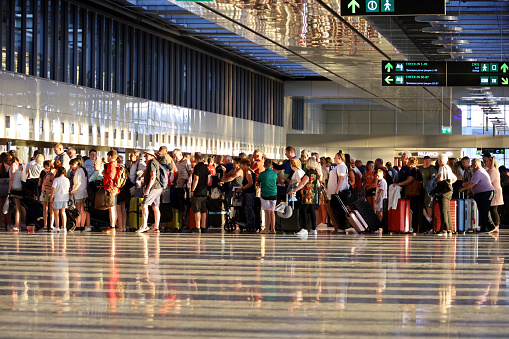 Dalaman, Turkey​ -​ July 2022: Passengers standing with luggage in queue in the Dalaman airport terminal