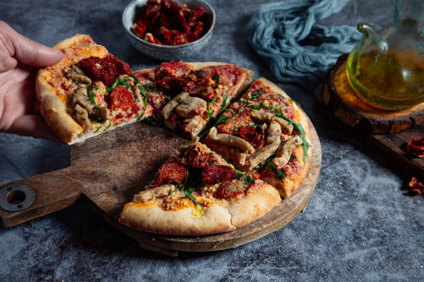 istock Man's hand picks up a slice of delicious pizza on a rustic table. 1409911765