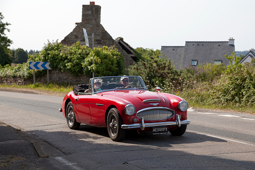 Kerlaz, France - July 17 2022: Retired couple cruising in a red Austin-Healey 3000 Mark III BJ8 sports convertible.