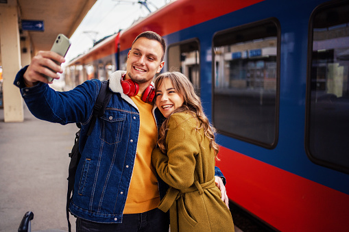 Young couple taking selfies while waiting on train station
