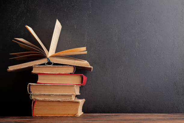 istock Old books on wooden table and blackboard 1409914882