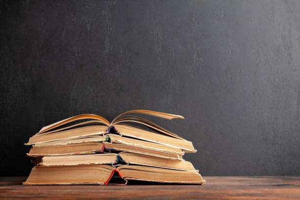 istock Old books on wooden table and blackboard 1409914896