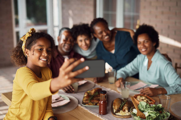 istock Happy black multi-generation family taking selfie while gathering for lunch at dining table on patio. 1409916060