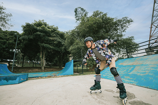 Asian Chinese gay Man practice inline skating at skateboard park during weekend