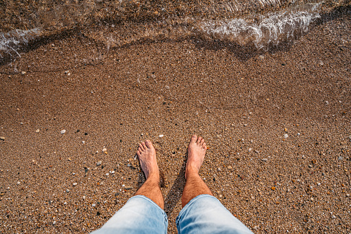 Holiday concept. Woman feet close-up relaxing on beach, enjoying sun and splendid view