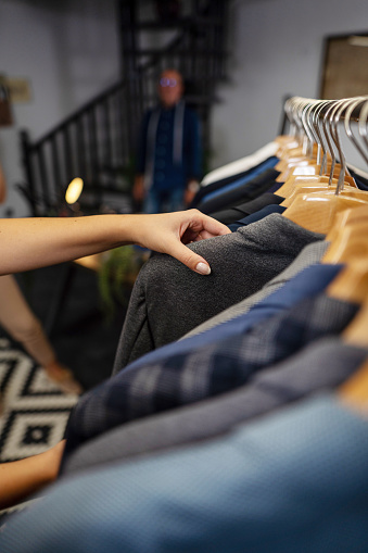 Close up photography of female worker trying to find best suit in the store