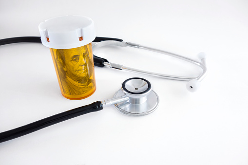 Stethoscope, dollar roll and a pill box on white background