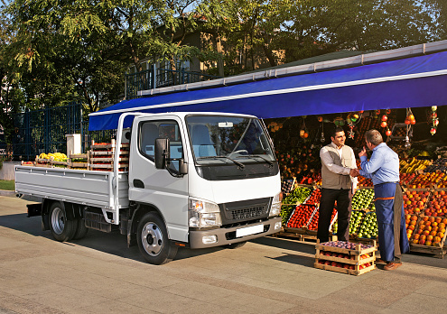Pick up truck in front of a grocery store with people working( the truck design is manipulated for copyright concerns)
