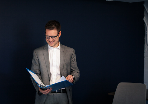 Male businessman in his 30s looking through a file with documents