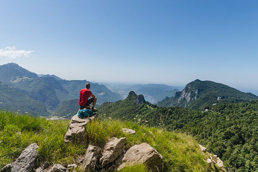 Lonely hiker sitting on top mountain looking at panorama
