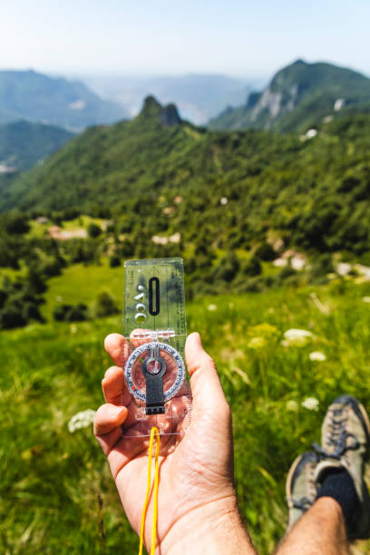 istock Human hiker hand with compass, forest in valley background 1409923322