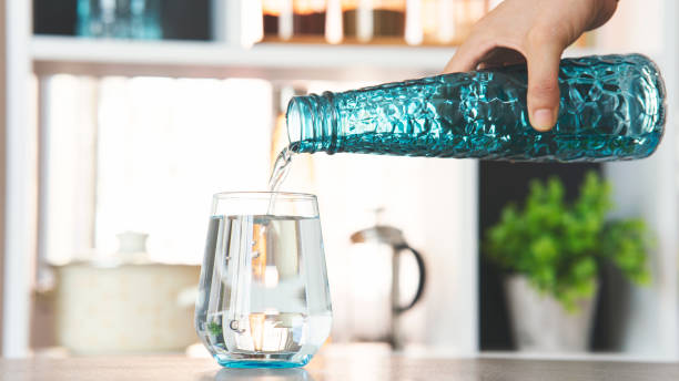 derramando água de garrafa de água em vidro na cozinha - pouring water carafe glass - fotografias e filmes do acervo