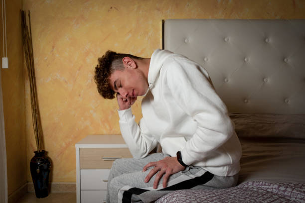 istock Young man reading book and studying while sitting on the bed at home. 1409924782