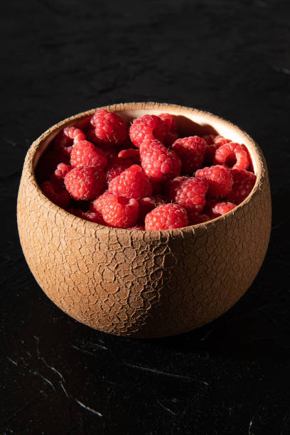 Red raspberry in a plate on a dark background. Fruit berries background. Summer food background.
