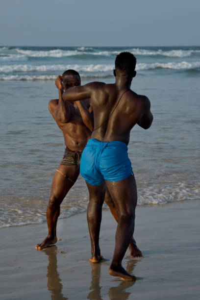 A group of wrestlerson the seashore Dakar. Senegal. October 13, 2021. A group of Senegalese wrestling fighters Laamb on the sandy seashore conducts a ritual dance before the fight, showing the opponent strength. wrestlers uniform stock pictures, royalty-free photos & images