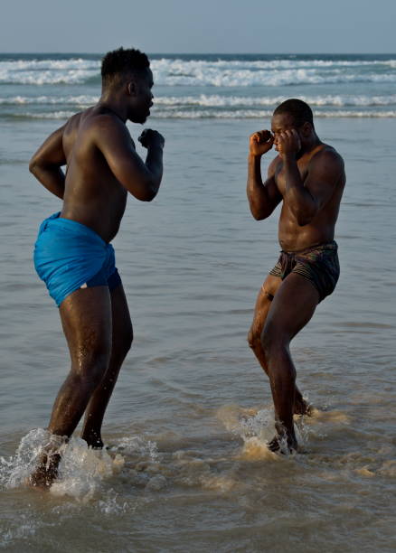 A group of wrestlerson the seashore Dakar. Senegal. October 13, 2021. A group of Senegalese wrestling fighters Laamb on the sandy seashore conducts a ritual dance before the fight, showing the opponent strength. wrestlers uniform stock pictures, royalty-free photos & images