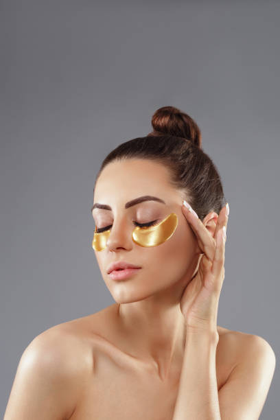 Beauty woman applying golden anti-aging under-eye mask stock photo
