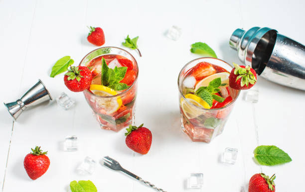 istock Summer refreshing mojito cocktail with strawberry, mint and lime with shaker for whipping drinks on a white wooden table 1409931138