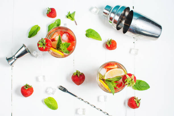 istock Summer refreshing mojito cocktail with strawberry, mint and lime with shaker for whipping drinks on a white wooden table 1409932296