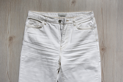 White denim jeans pants on the wood background