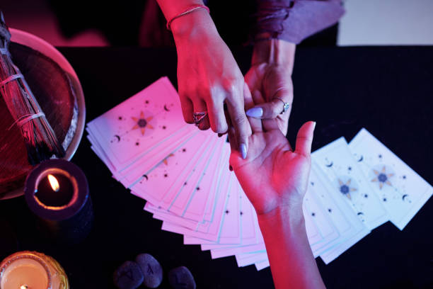 Mysterious Palmstry Session Fortune teller pointing at love line on palm of female client fortune telling stock pictures, royalty-free photos & images