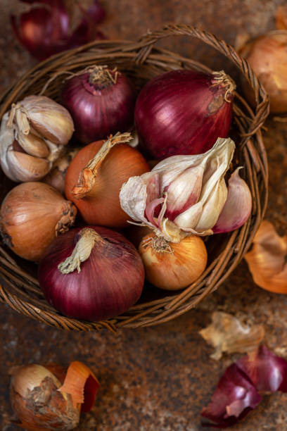Onions and garlic in a wicker basket on an old background. Rustic, vintage style