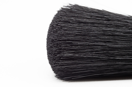 macro shot of the black bristles of a make-up brush, on a white background with much shadows