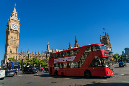 THE HOUSES OF PARLIAMENT, LONDON, ENGLAND, JUNE 22, 2022. Big Ben, The Palace of Westminster and a traditional Red London Bus, Parliament Sqaure, London, England.