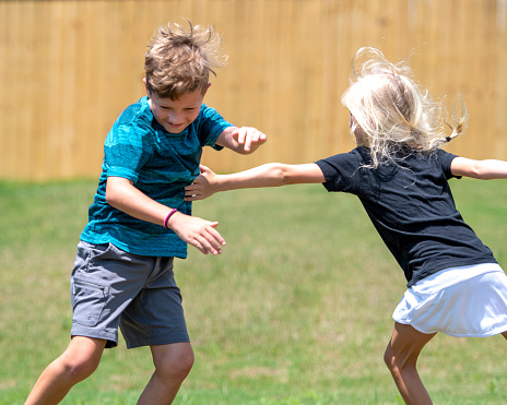 Boy and Girl Playing Tag in Grass Yard Outside