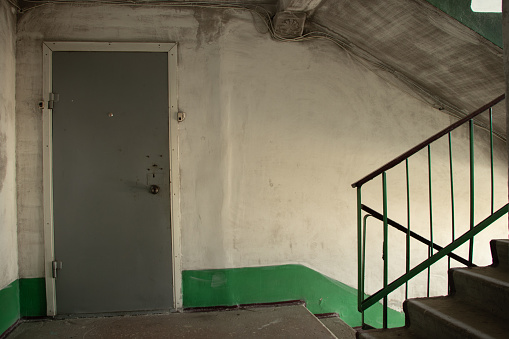 old dirty soviet entrance in an apartment building after a fire, a corridor in the entrance, a staircase