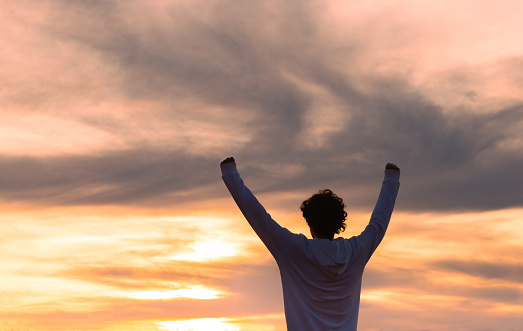 Silhouette of a man feeling strong and determined to overcome life's challenges with sunset in the background