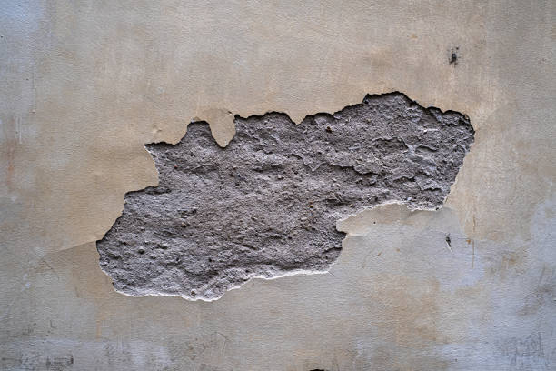 Cracked plaster on the old wall. Vintage grungy facade pattern. Old surface of cement, broken stucco.