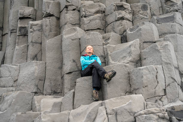 istock Woman sitting on Gardar Basalt Columns on Reynisfjara Black Sand Beach 1409951813