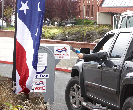 A voter dropping his ballot in a drive-up drop box on election day