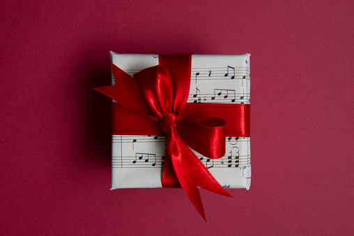 The gift box covered with musical note paper on red background.