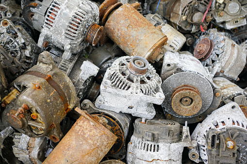A pile of rusty and oxidized used car starters and alternators, scrap electric motors