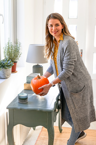 beautiful middle aged woman in home interior with pumpkin