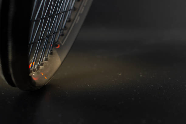 Black and orange tennis racket on a black background