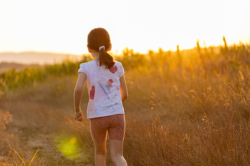 Photo of little girl athlete running at sunset in nature