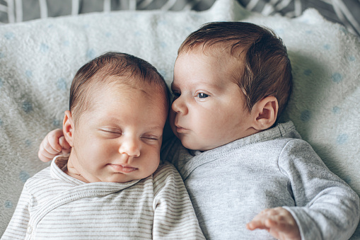 Cute baby girl lying on the bed whit her brother at home