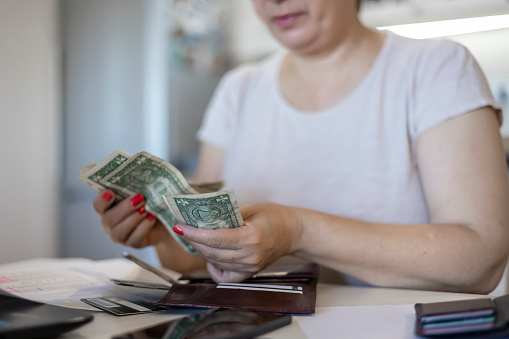 Shot of an adult woman counting money to pay her bills