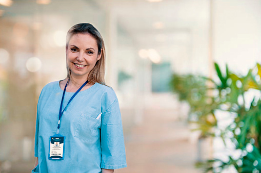 Smiling confident female doctor in Hospital. Portrait of Woman medical nurse or caregiver in bright modern health clinic. Front view. Copy space