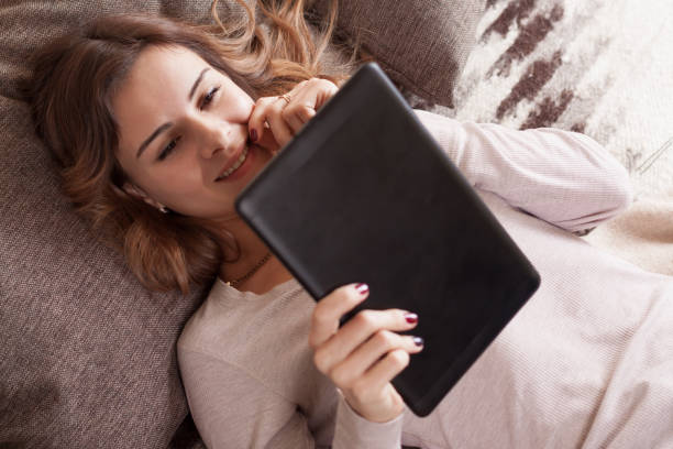 Cтоковое фото Счастливая молодая женщина с планшетом PC лежа на диване